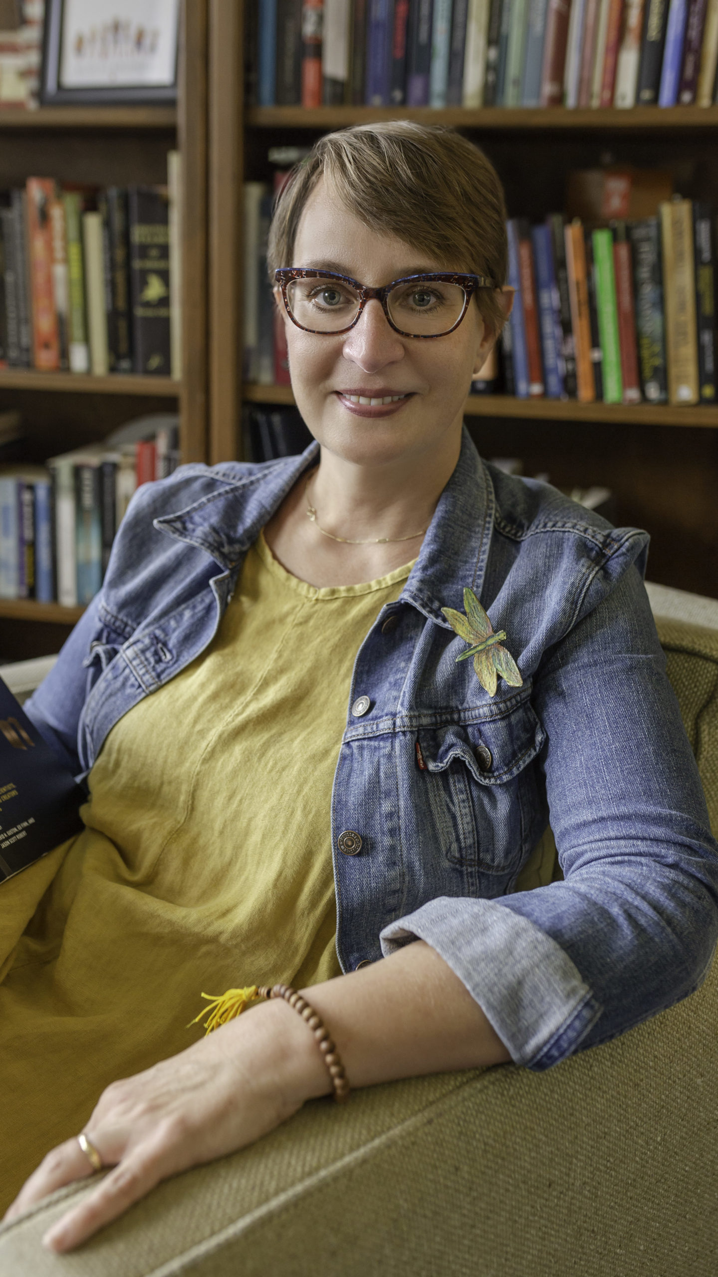 Sabrina Starnaman, sitting, in front of bookshelf